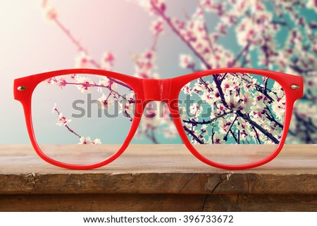 hipster glasses on a wooden rustic table in front of the cherry tree blossom

