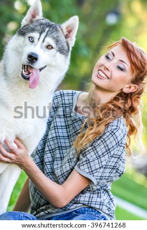 Happy young woman sitting with her dog on grass in park