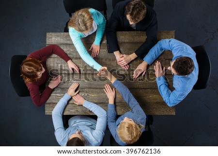 Top view creative photo of business people sitting at dark wooden vintage table. Business people having meeting. Concept for successful teamwork