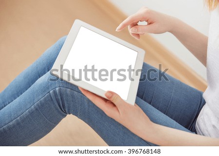 Young female student sitting in a university recreation hall using touch pad, freelancer girl working on her digital tablet with blank tablet screen, hipster woman using touchscreen device