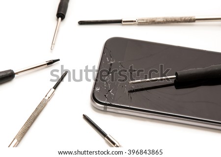 Broken smartphone and small screwdrivers for repair on white background