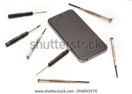 Broken smartphone and small screwdrivers for repair on white background
