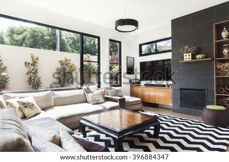 Monochrome living room with wood and grey tiling accents and chevron pattern rug Royalty-Free Stock Photo #396884347
