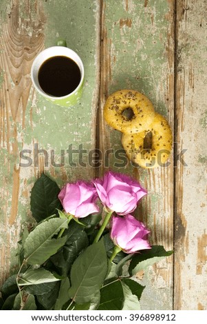 Pink roses, coffee and two donuts on old wood desk