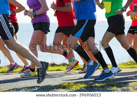 Group of runners compete in the race on coastal road Royalty-Free Stock Photo #396906013
