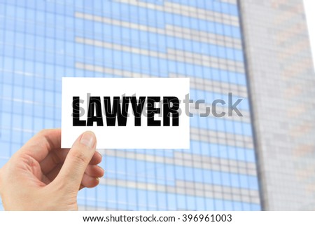 word lawyer on white card in hand modern office building background