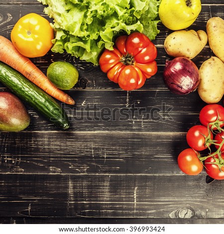 Composition with assorted raw organic vegetables on black wooden background