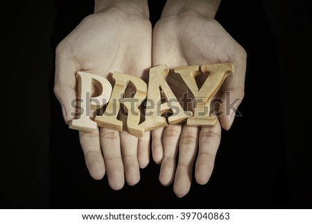 Close up of prayer hands showing a word of pray in dark background