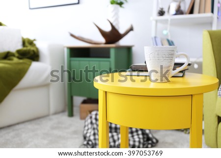 Cup of coffee with books on table in interior of living room
