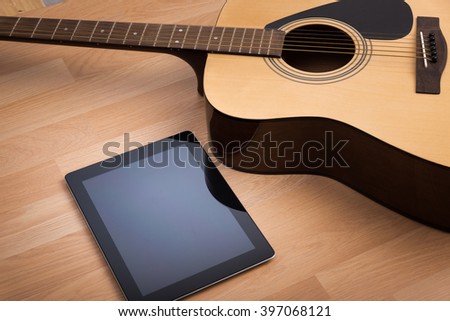 Acoustic guitar with digital tablet on the wooden table