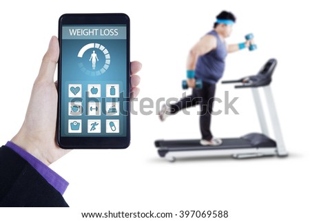 Picture of weight loss application on the mobile phone screen with overweight man exercising on treadmill