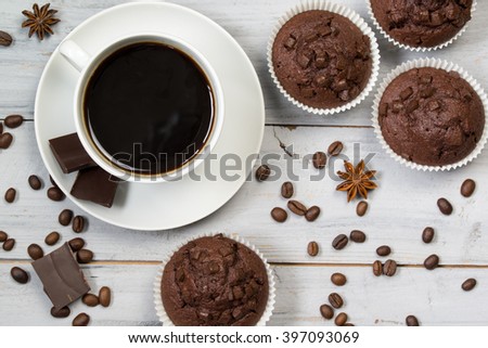 Cup of black coffee, coffee beans, anise stars and chocolate muffins, top view