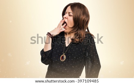 Woman yawning over ocher background