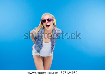 Cheerful stylish female teenager posing over blue background