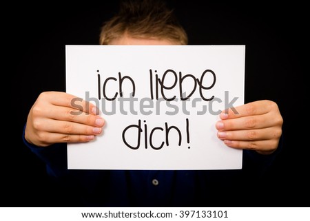 Studio shot of child holding a sign with German words Ich liebe Dich - I Love You