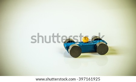 Retro styled or retro color wooden toy race car on empty background. Concept of dream car ownership and financing. Slightly de-focused and close-up shot. Copy space.