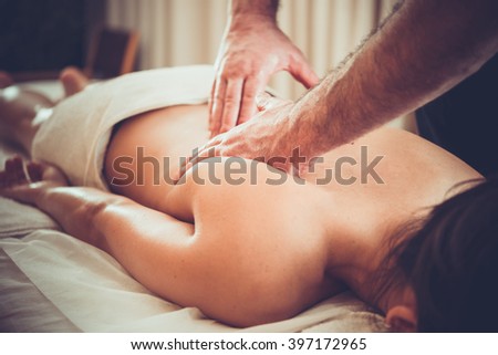 Woman enjoying relaxing back massage in cosmetology spa centre. Beauty treatment, body care, skin care, wellness, wellbeing concept. Toned picture