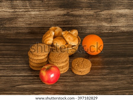 Cookies, fruits and croissants on a wooden background .