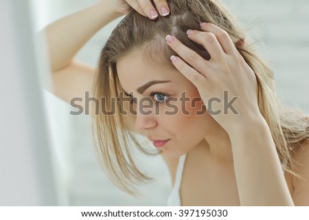 nervous girl looking in the mirror her scalp Royalty-Free Stock Photo #397195030