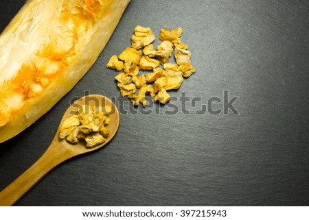 Slice pumpkin and wooden spoon on a dark background. The view from the top.