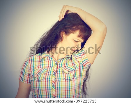 young woman, smelling, sniffing her armpit, something stinks, very bad foul odor isolated grey background. 