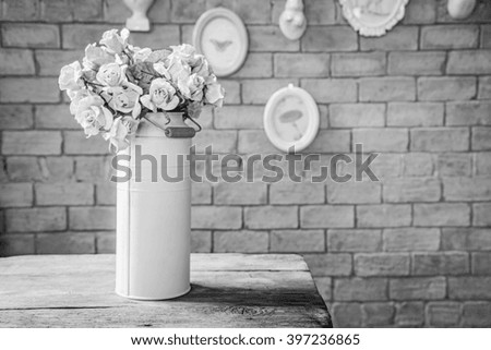 Roses in metal tank on top wood table in front of red brick wall.