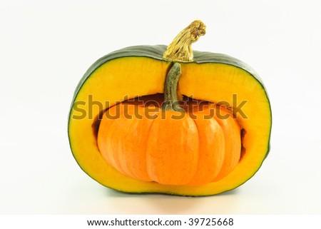 Picture of orange mini pumpkin stuffed inside half of bigger green pumpkin.