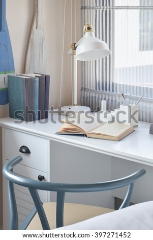 white table with wooden chair books and lamp in modern working area at home
