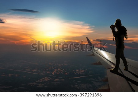 silhouette of photographer taking photo on airplane wing can see Fantastic sun light over cityscape, Challenge concept