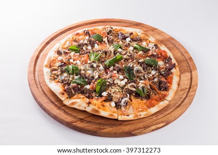 Pizza with mint on a wooden circular board isolated on white background