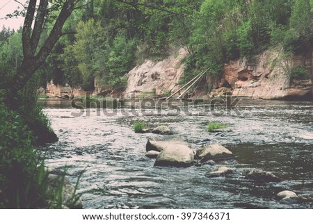sandstone cliffs by the river in Gauja national park in latvia - vintage film effect
