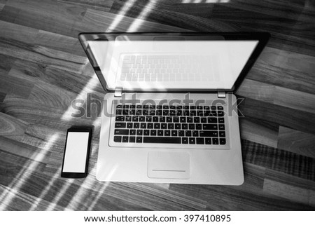 Laptop on a wooden table with a mobile phone