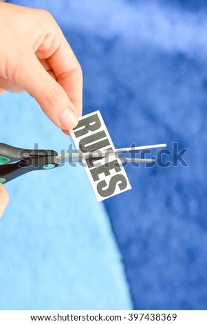 Woman hands cutting with scissors a printout reading "RULES"