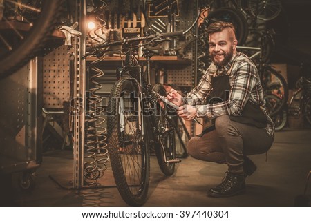 Stylish bicycle mechanic making notes in clipboard in his workshop. 