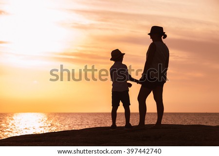 Mother and son silhouettes at the sunset time