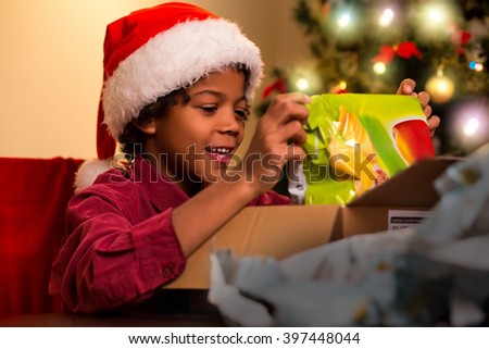 Happy darkskinned boy opens present. Black kid opening Christmas present. Just what I wanted. Christmas brings joy.