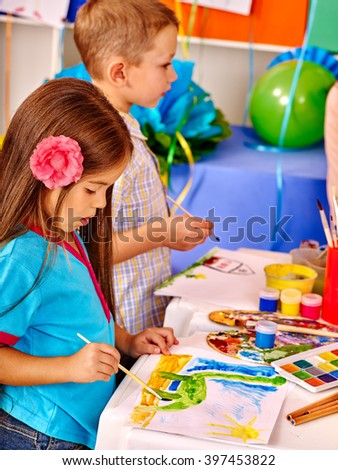 Little girl and boy with brush painting on table in  kindergarten . 
