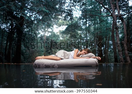 A hidden place. Sleeping woman in deep forest lies on airbed Royalty-Free Stock Photo #397550344