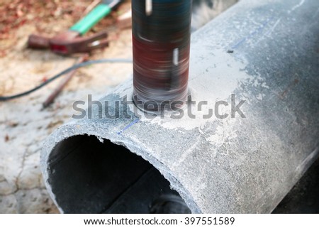 Workers use a drill to make a hole for cement pipe.