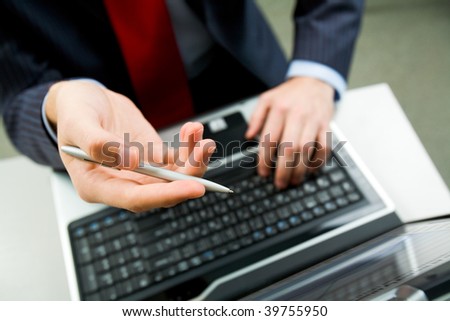 Above angle of male hand with pen pointing at laptop screen during discussion