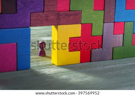 Abstract man in the doorway. Colorful wall of wooden puzzles. Construction of Tetris shapes.
