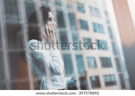 Photo business woman wearing modern suit, talking smartphone and holding papers in hands. Open space loft office. Panoramic windows background. Horizontal mockup. Film effect