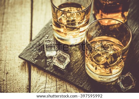 Whiskey with ice in glasses, rustic wood background, copy space Royalty-Free Stock Photo #397595992