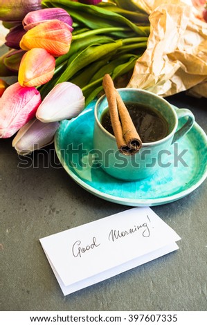 Cup of coffee with tulip flowers on rusty background