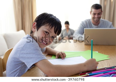 Boy painting and father using a laptop and mother reading at home