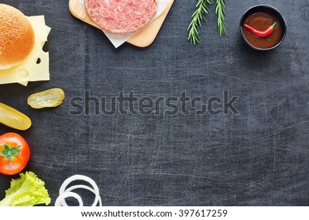 Minced beef, bun, cheese, tomato, lettuce, onion, pickle, hot BBQ sauce. Home handmade hamburger. Black board background. Space for text.