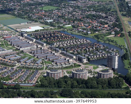 Aerial view of a new district in Alkmaar, Netherlands with a lot of colorful houses. The district is called VROONERMEER and a lot of buildings have solar panels. In the back it's Sint Pancras.