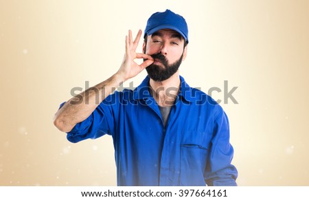 Plumber making silence gesture over ocher background