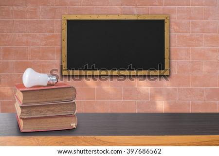 books on wooden table and  black board on brick wall texture background