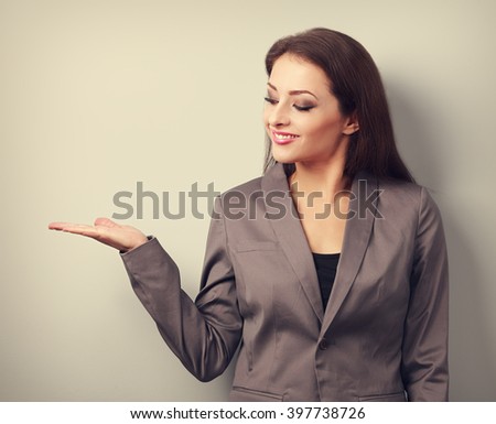Happy business woman holding something empty in hand and demonstration. Toned portrait